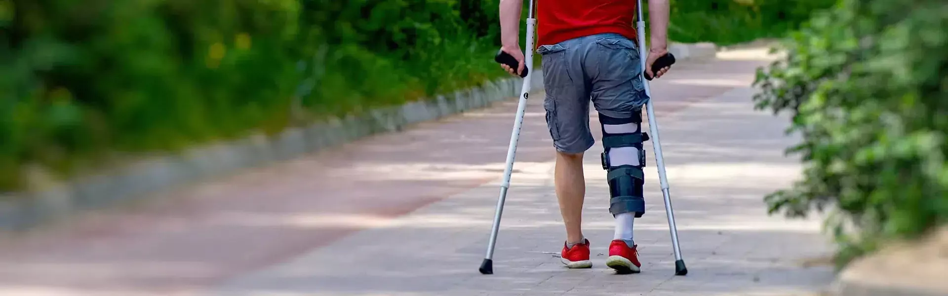 determined man knee brace using crutches