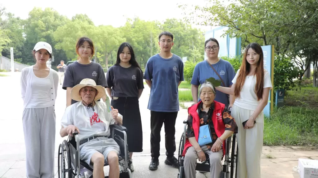Volunteers and two elderly people sitting in wheelchairs