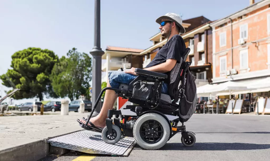 Male tourist on wheelchair crossing over the threshold ramp on the seaside promenade.