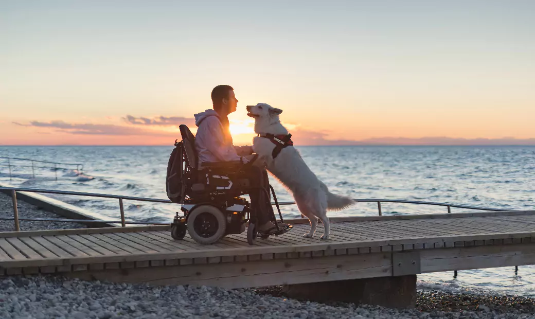 A man in an electric wheelchair is sitting by the seaside.