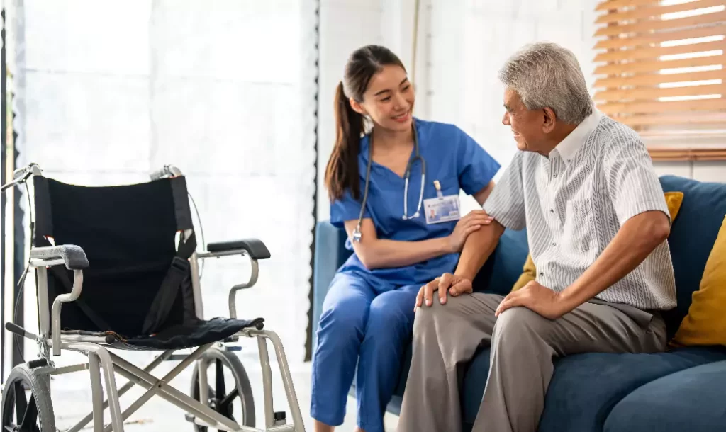 Asian young caregiver take care senior man on wheelchair in house.