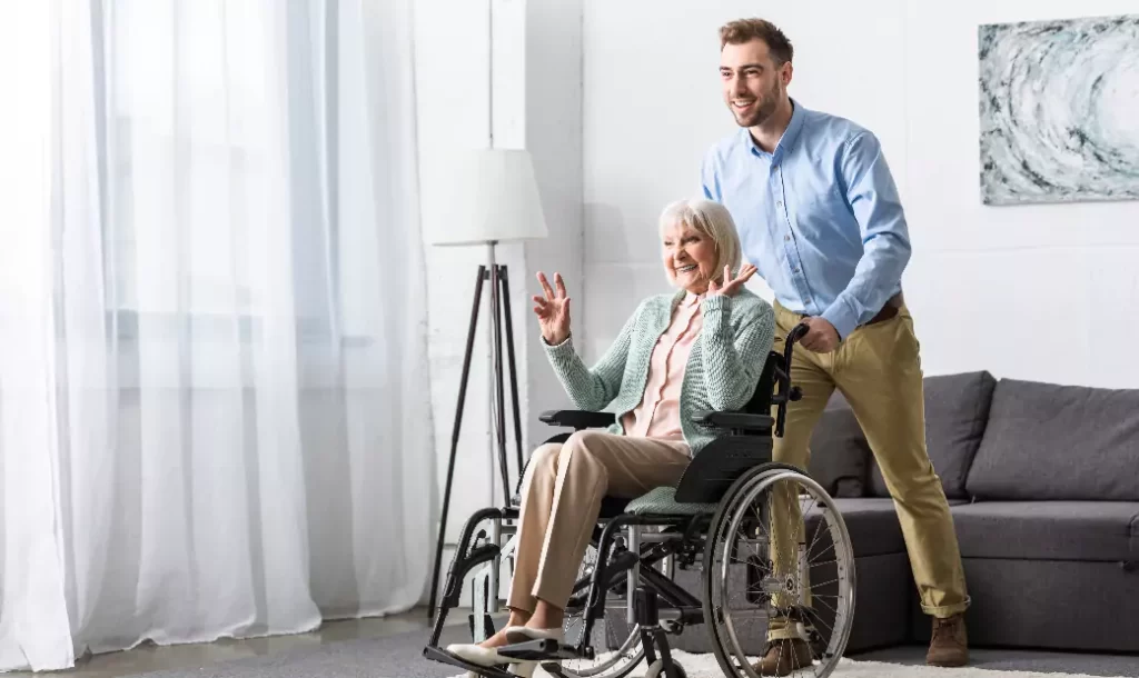 smiling-man-carrying-disabled-senior-mother-on-wheelchair