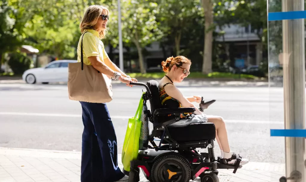 woman-pushes-her-friend-electric-wheelchair