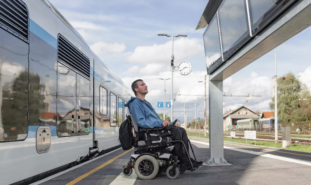 A disabled person in an electric wheelchair looking at the train schedule.